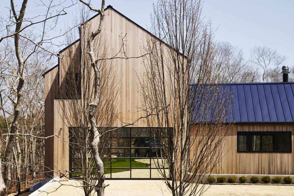 Tall gable of a cedar home with a standing seam roof on the lower wing