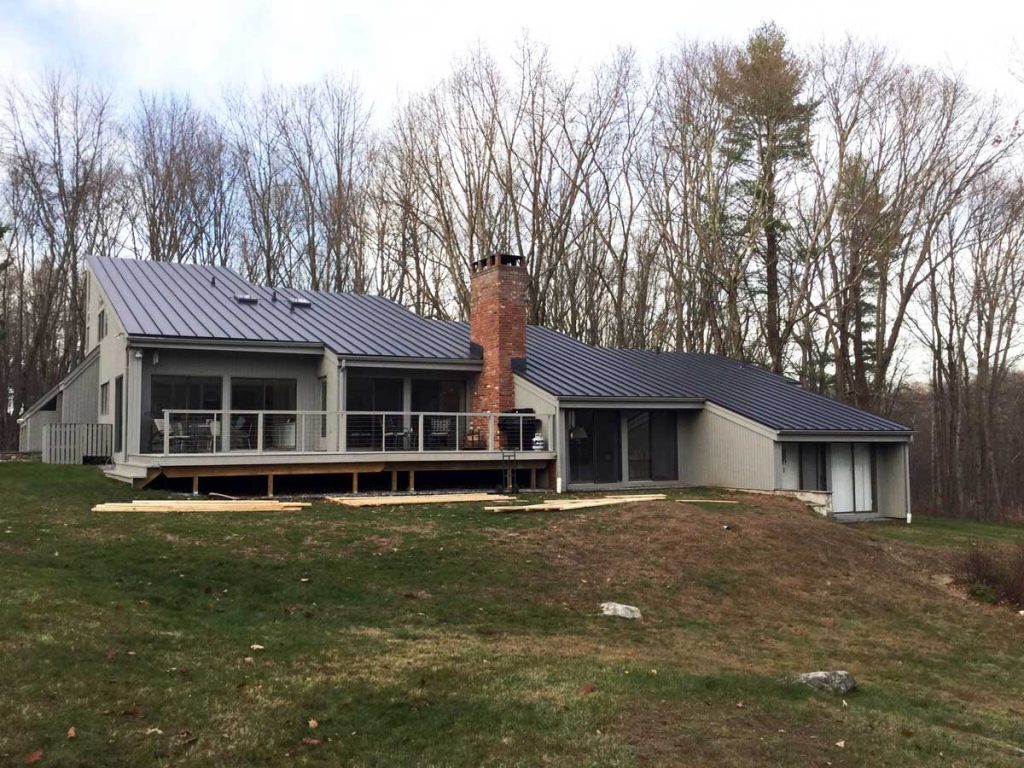 Charcoal standing seam metal roof on a ranch-style home with a brick chimney