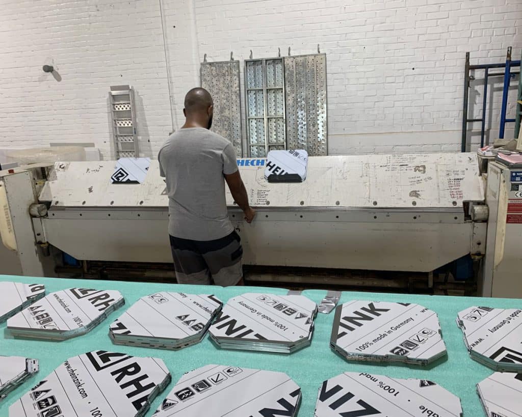 Sheet metal worker at a long folding machine with cut flashing pieces on a table