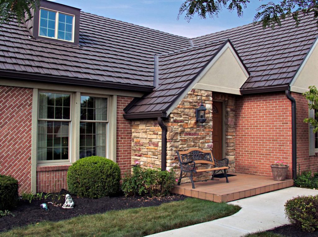 Brown painted metal shake shingles on a brick home with a stone entry