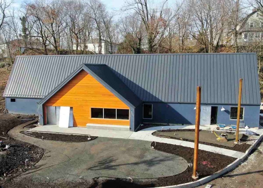 Commercial Metal Roofing Dark standing seam roof over a retail building with a wood-clad gable