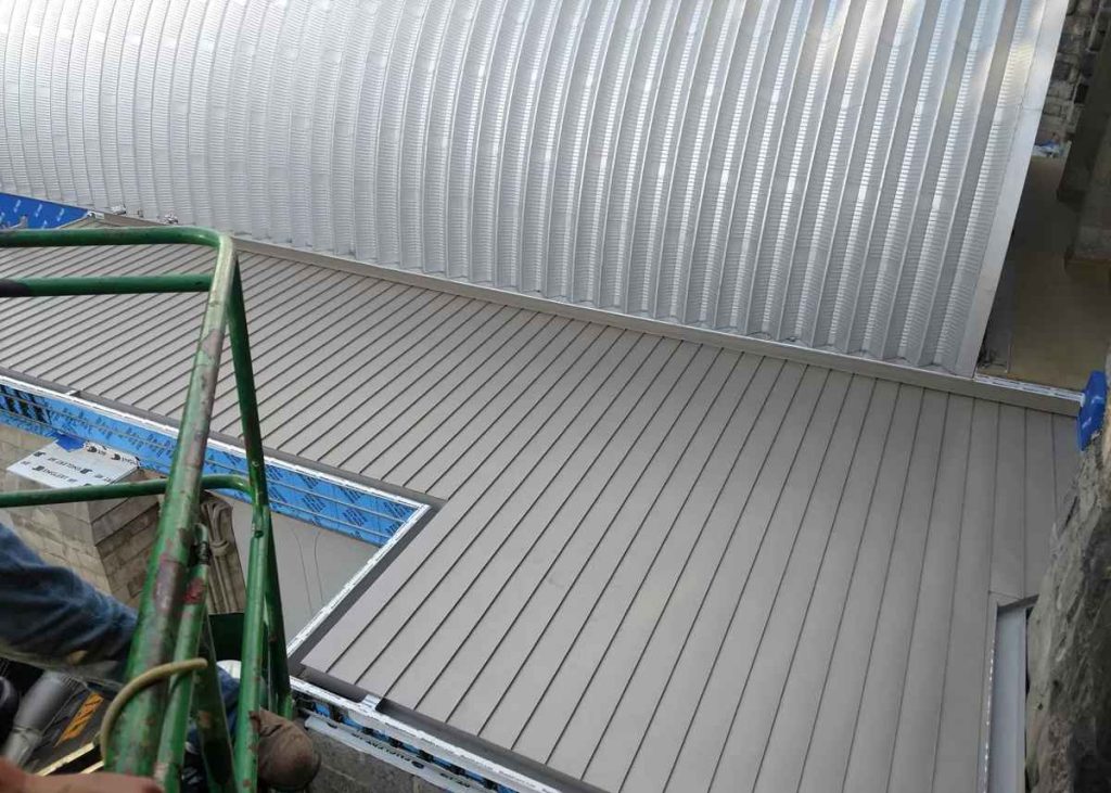 Light gray standing seam panels seen from the scaffolding