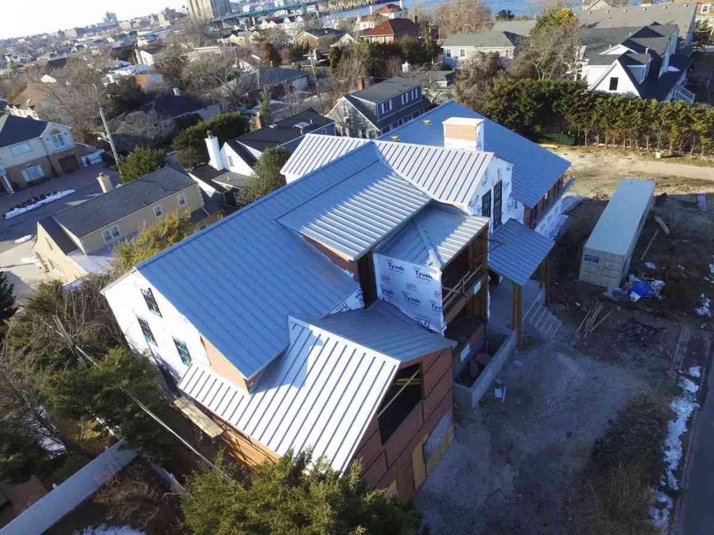 Gray standing seam roof with several hips and valleys seen from above