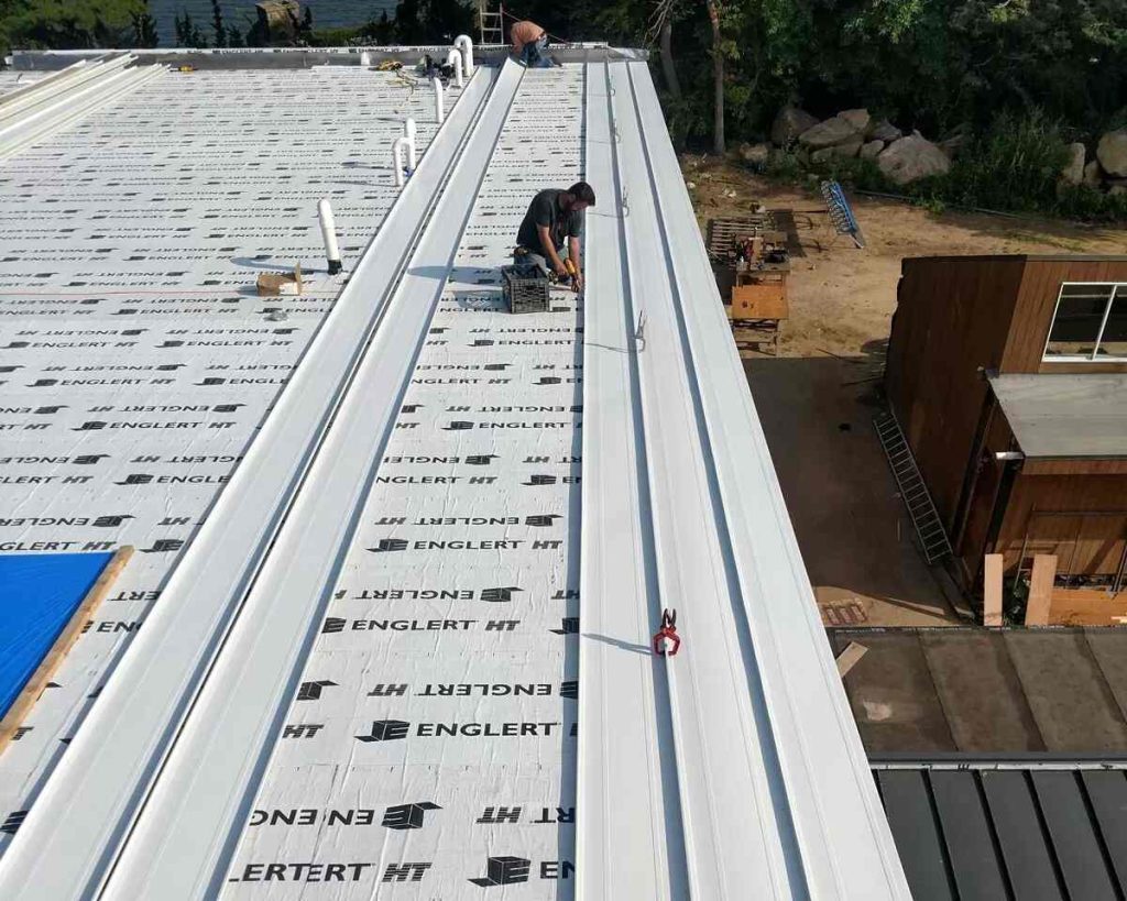 Standing seam panels going down over synthetic underlayment on a roof deck