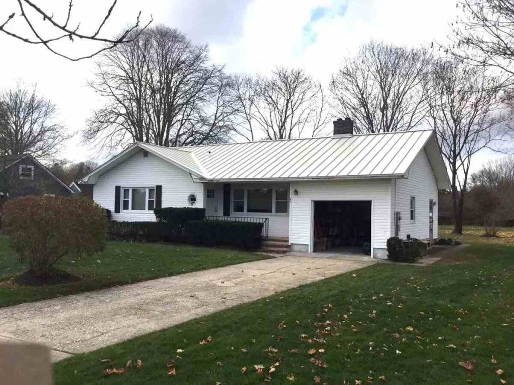 Single-story home with a white standing seam roof and a gravel drive