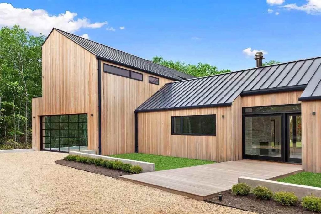 Dark standing seam metal roof on a barn-style home with cedar siding