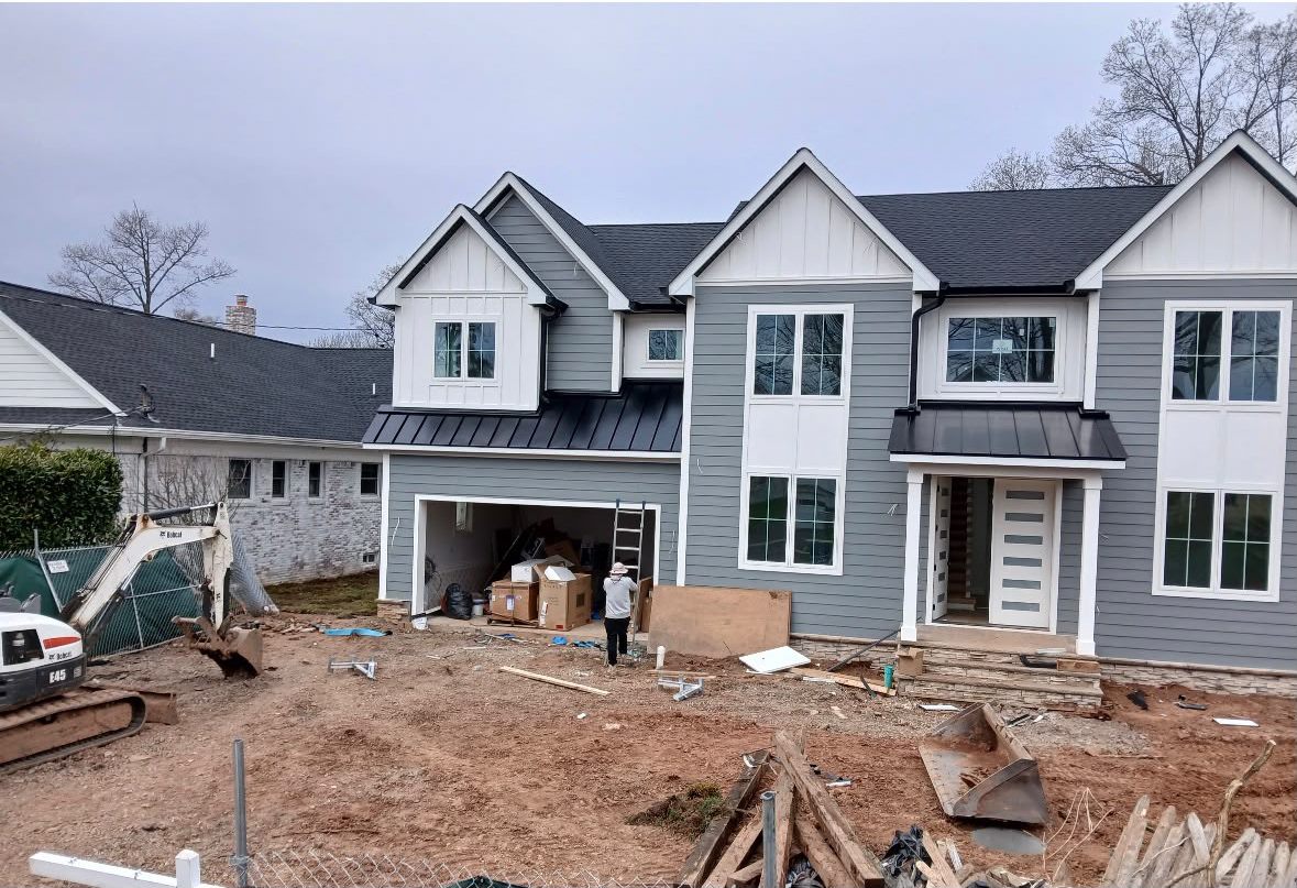 Black Standing Seam Garage and Porch Roofs on a Gray Home New home with gray siding and black standing seam roofs over the garage and front porch