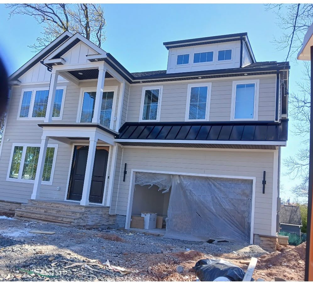 Long Standing Seam Roof Over the Garage of a Beige Home Long black standing seam roof over the garage of a two-story home with beige siding