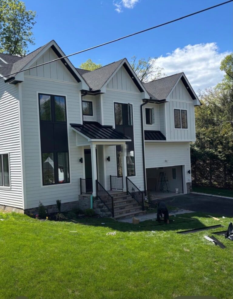 White farmhouse-style home with black standing seam porch and bay window roofs