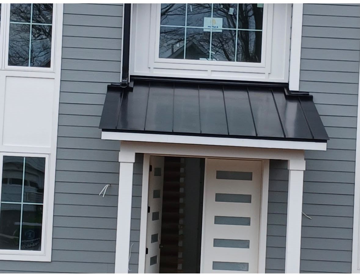 Black Standing Seam Garage and Porch Roofs on a Gray Home Black standing seam porch roof over a front door on a home with gray lap siding