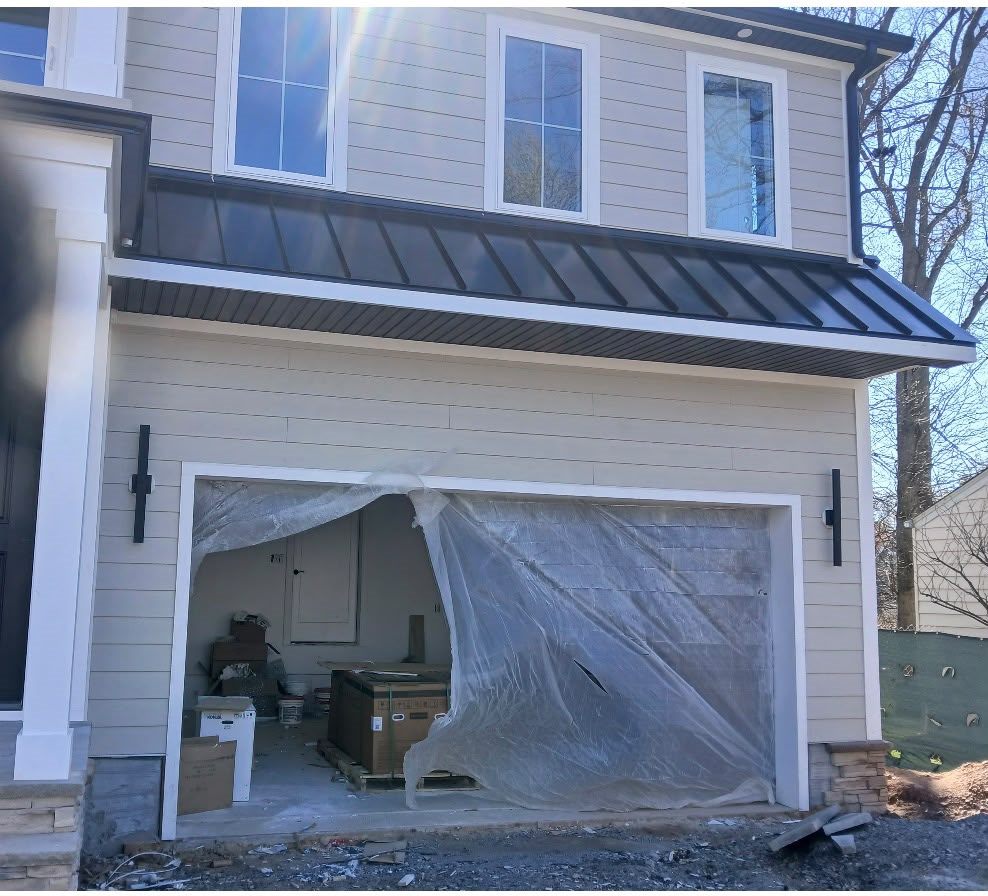 Long Standing Seam Roof Over the Garage of a Beige Home Black standing seam roof over a two-car garage door